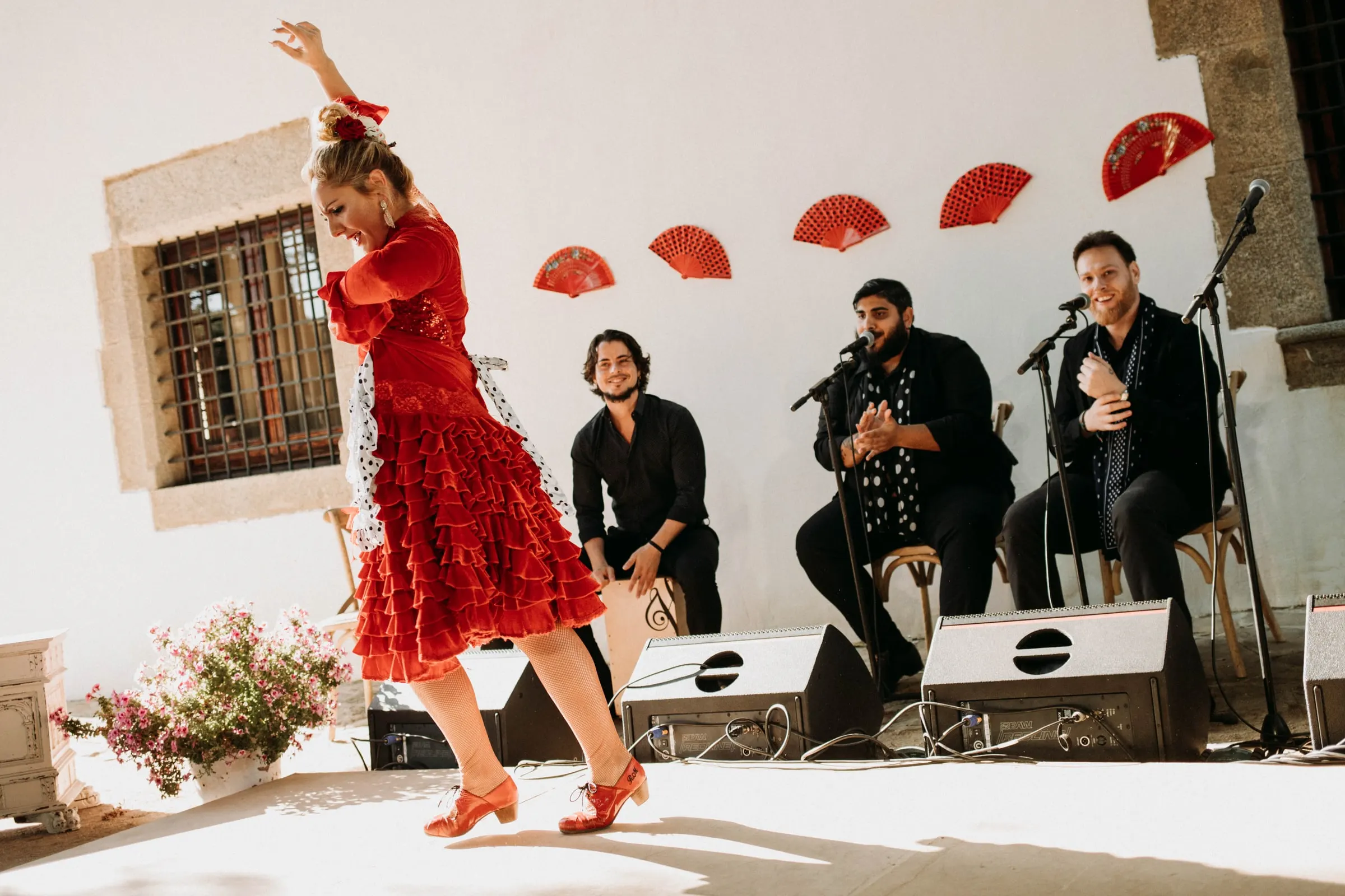 Una bailaora vestida de rojo con el brazo en alto y los músicos detrás, en una masía de Girona