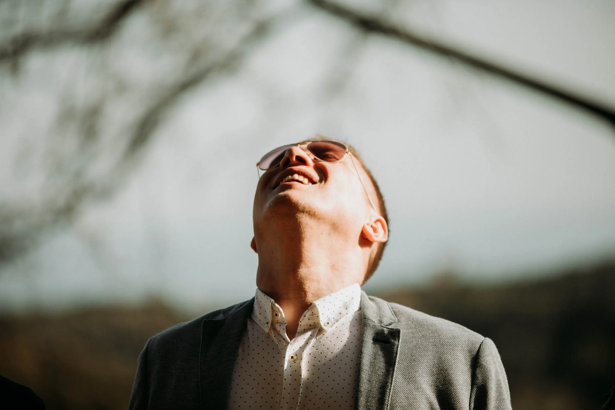 Un invitado con gafas de sol echa la cabeza hacia atrás de la risa, en una masía de Girona