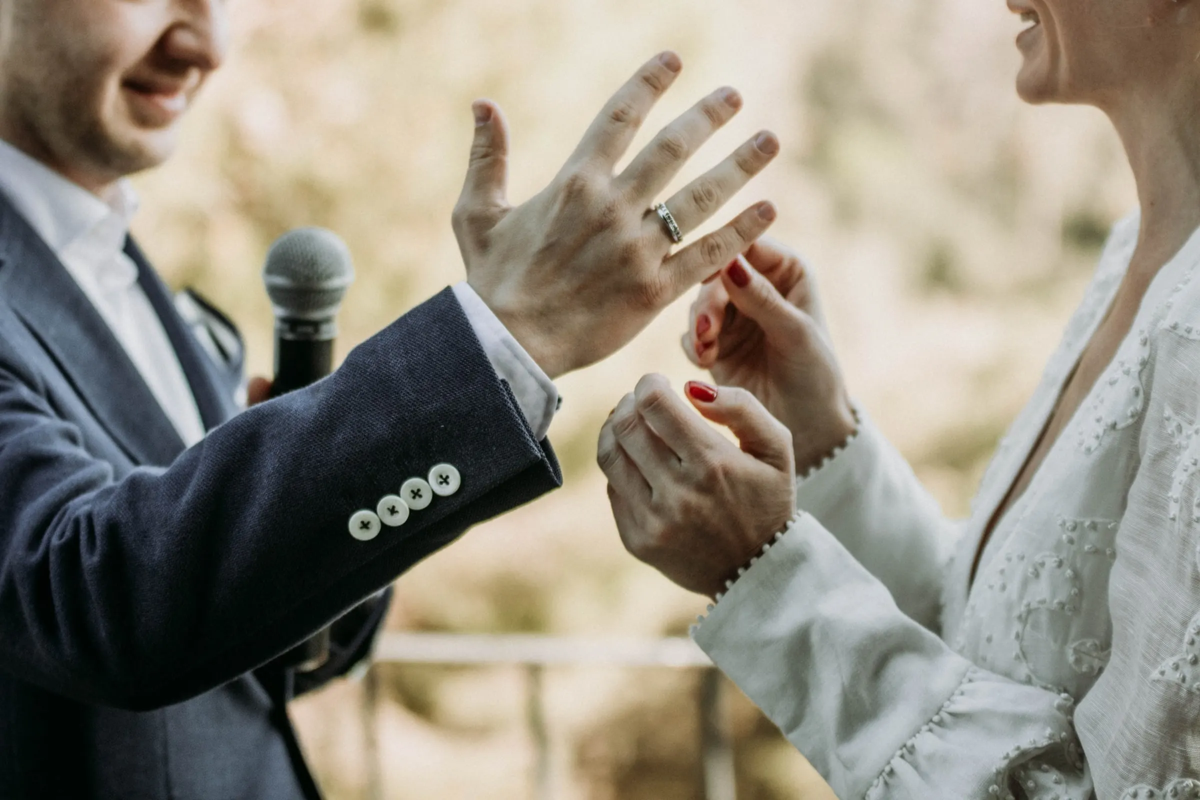 Detalle del novio enseñando su alianza mientras la novia le sujeta la mano, en una masía de Girona
