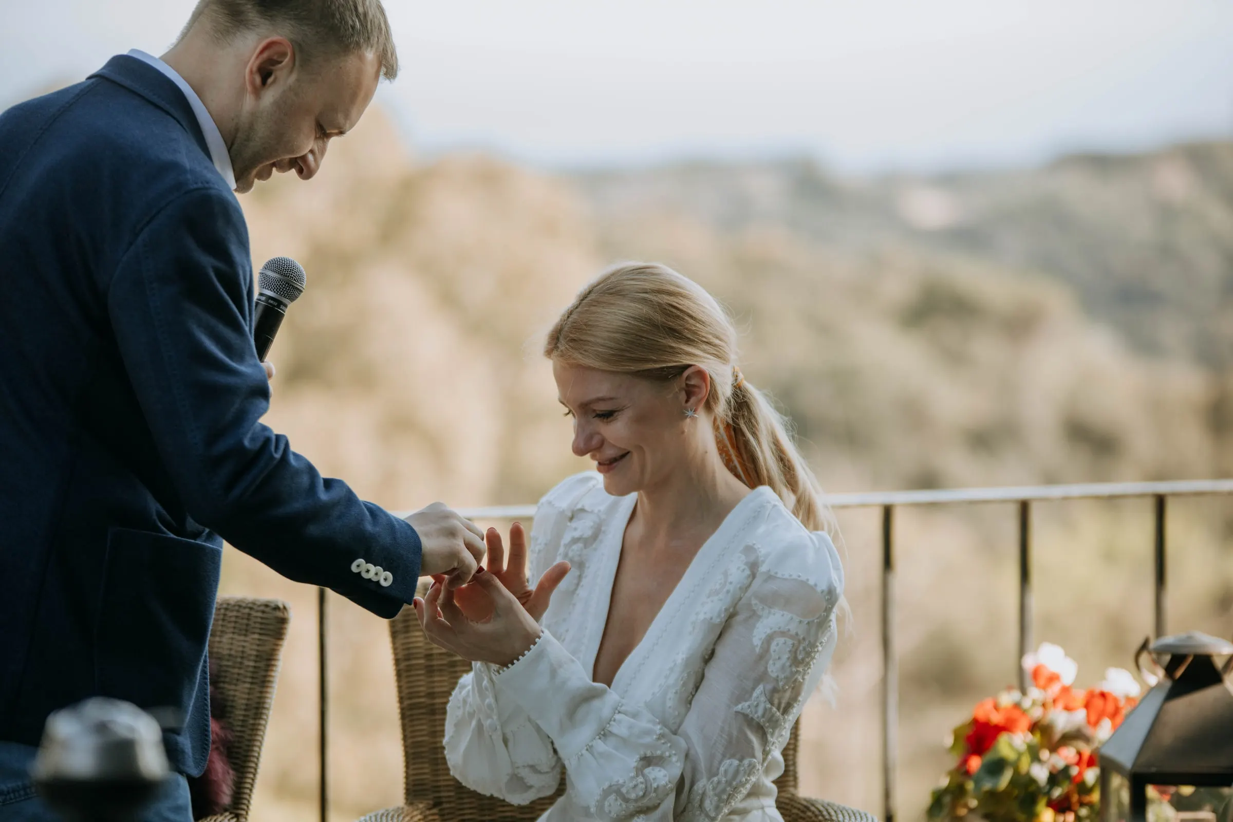 El novio se agacha para poner un anillo a la novia, sentada en la terraza de una masía de Girona