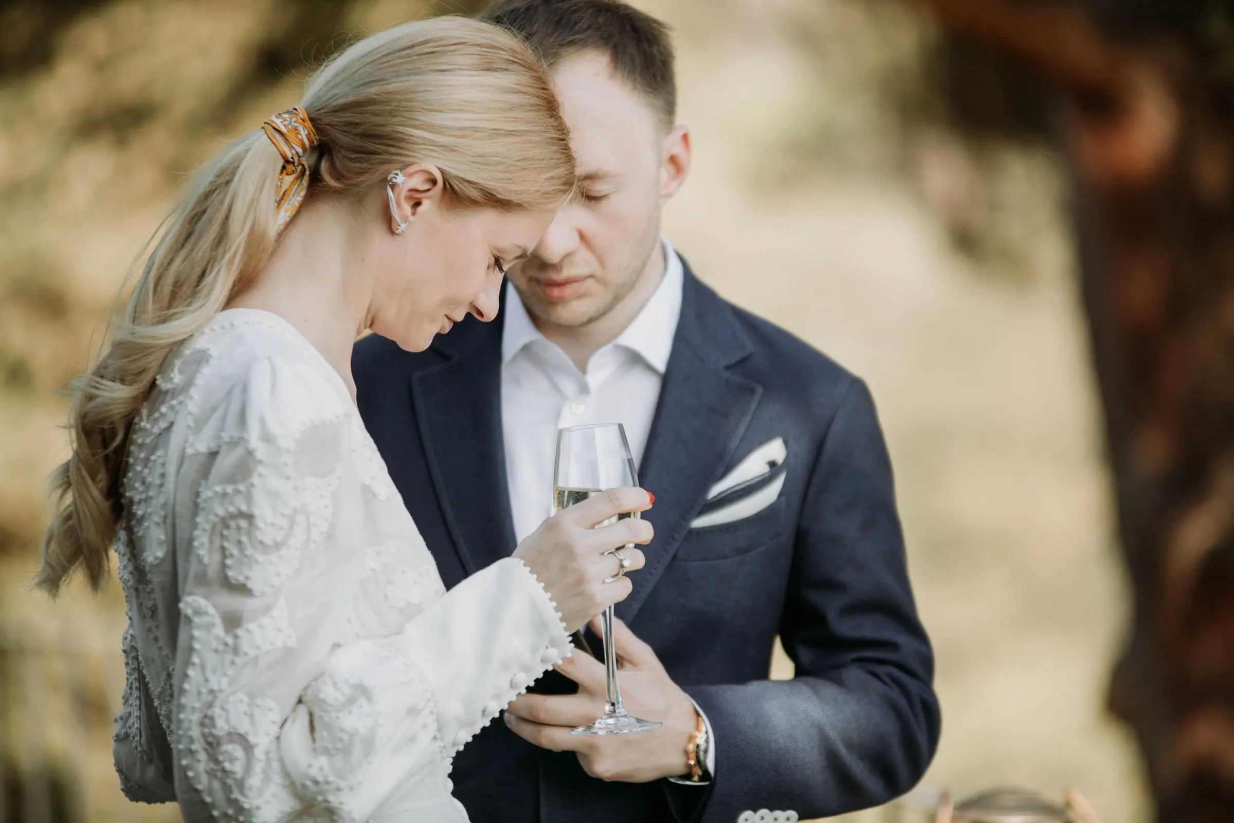 El novio apoya la cabeza en la de la novia mientras ella sostiene una copa, en una masía de Girona
