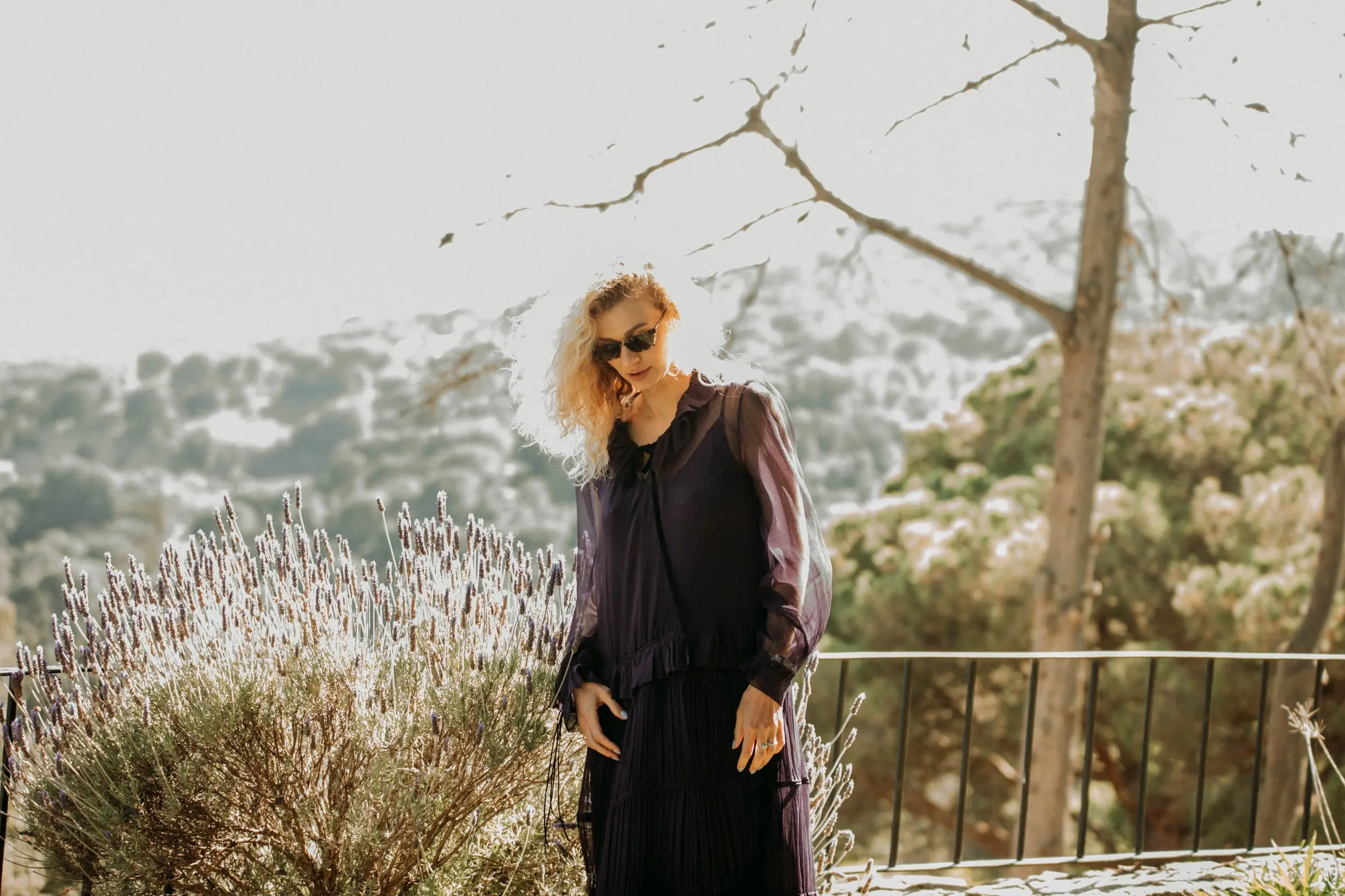 Una invitada con vestido morado y gafas de sol pasa junto a la lavanda en una masía de Girona