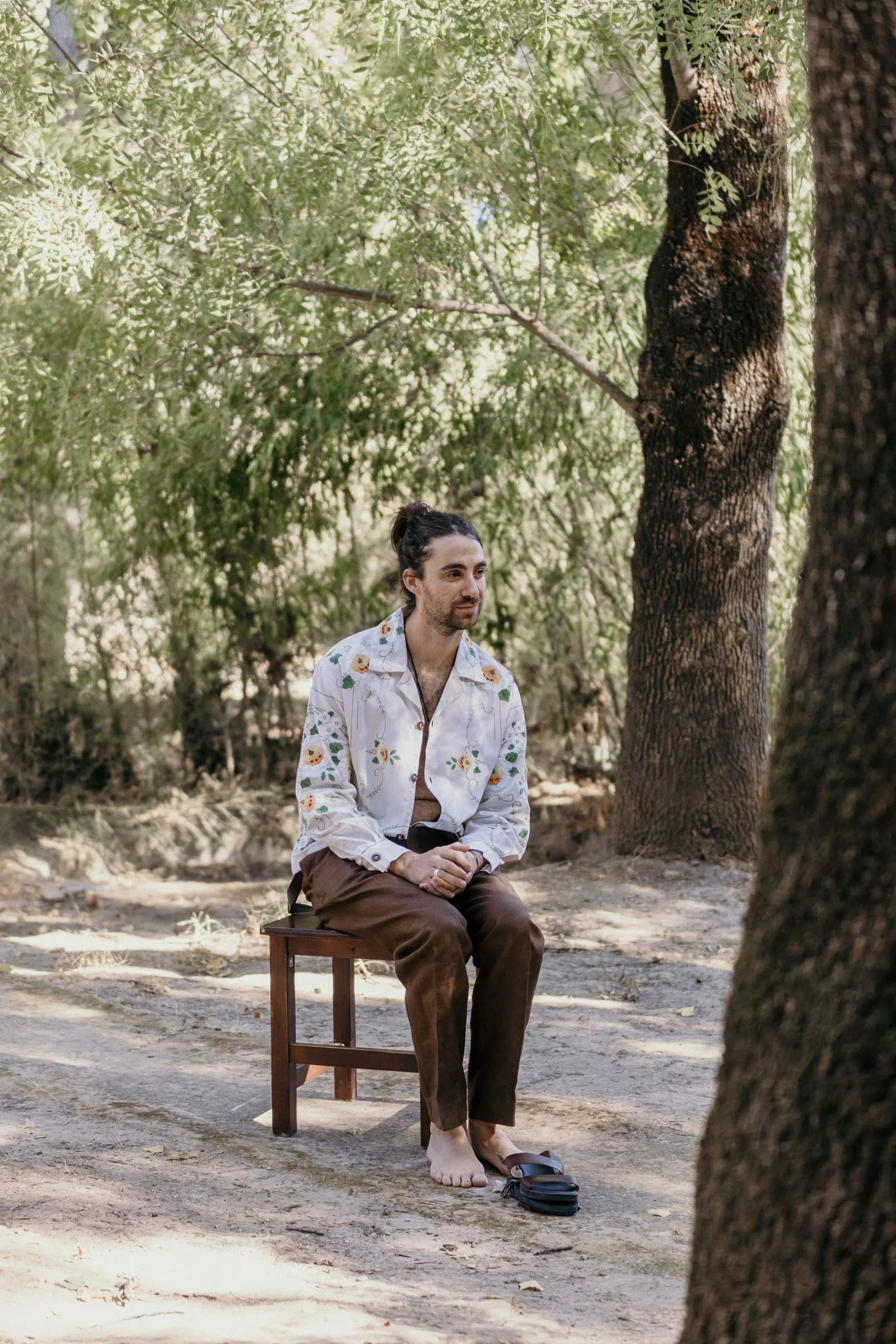 El novio sentado en una silla de madera bajo los árboles en Molino La Flor, Jimera de Líbar