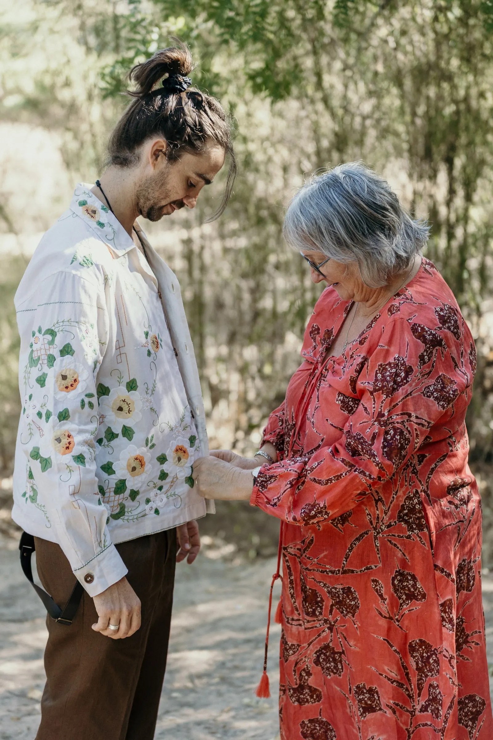 La madre del novio, con vestido rojo de flores, le coge las manos antes de la boda
