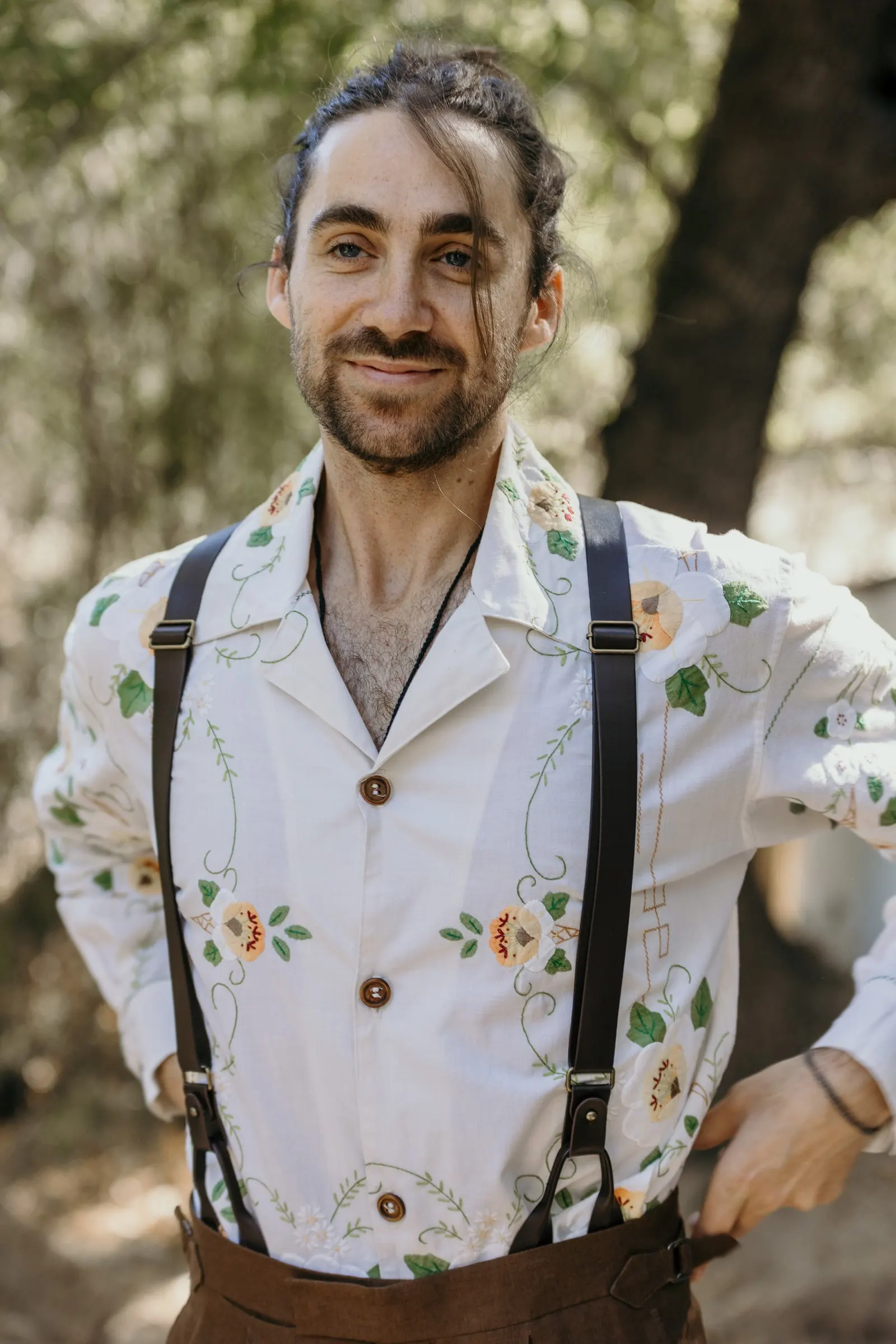 El novio sonriente, con tirantes y camisa bordada de flores, en la Serranía de Ronda