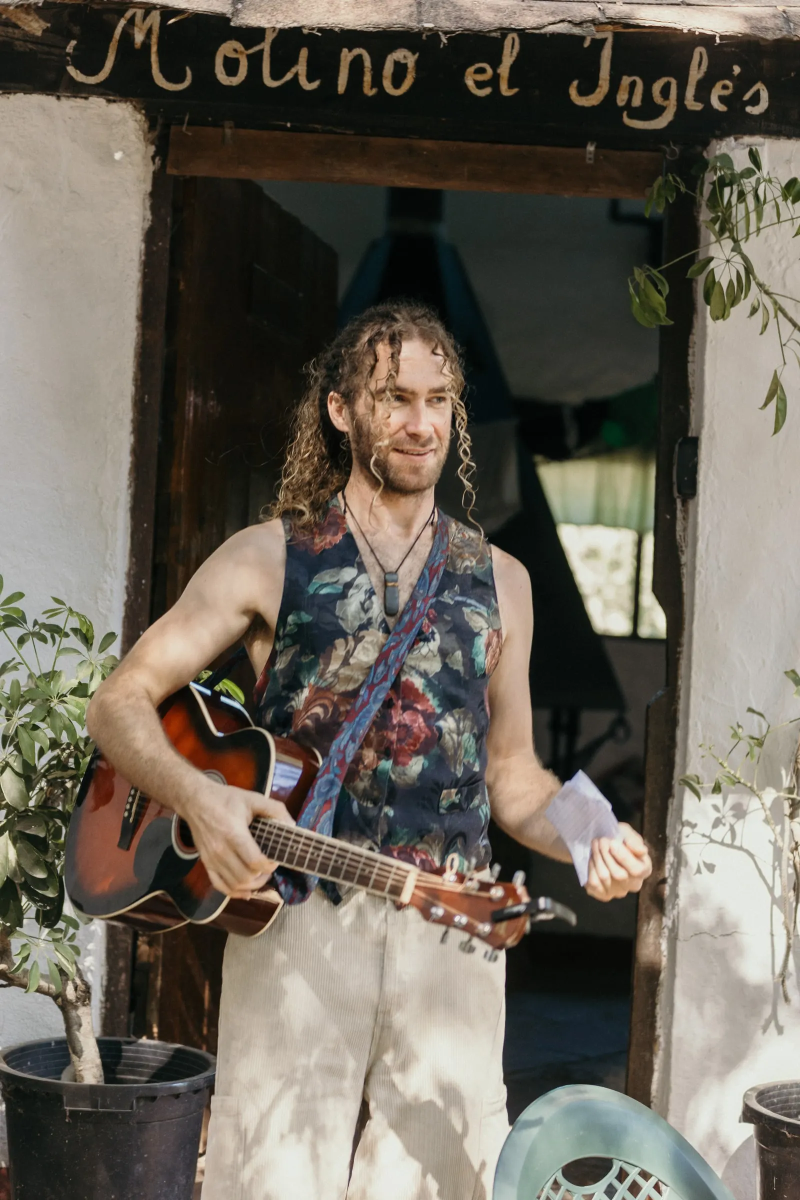 Un amigo con guitarra bajo el cartel pintado a mano «Molino el Inglés»