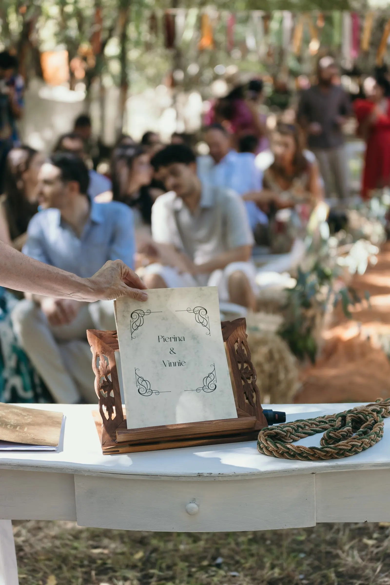 Carved wooden sign with the couple's names on the ceremony table, with a handfasting cord
