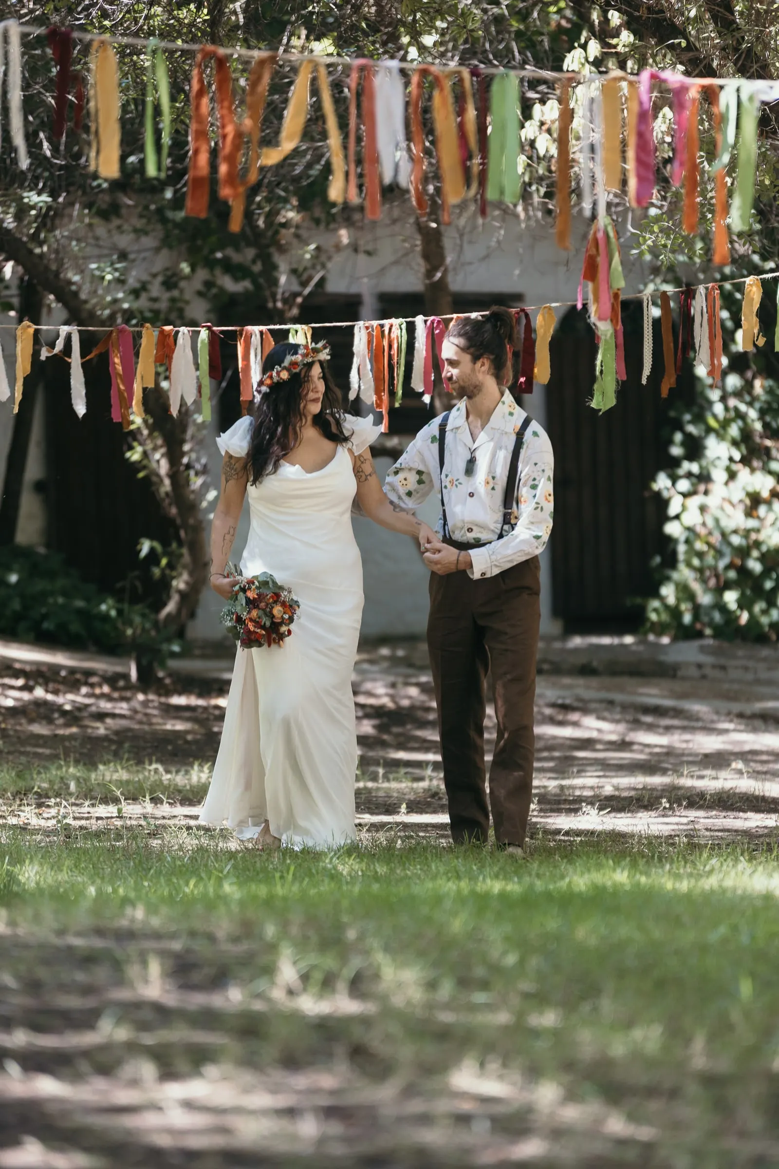 Los novios caminan juntos bajo las guirnaldas de cintas hacia su ceremonia
