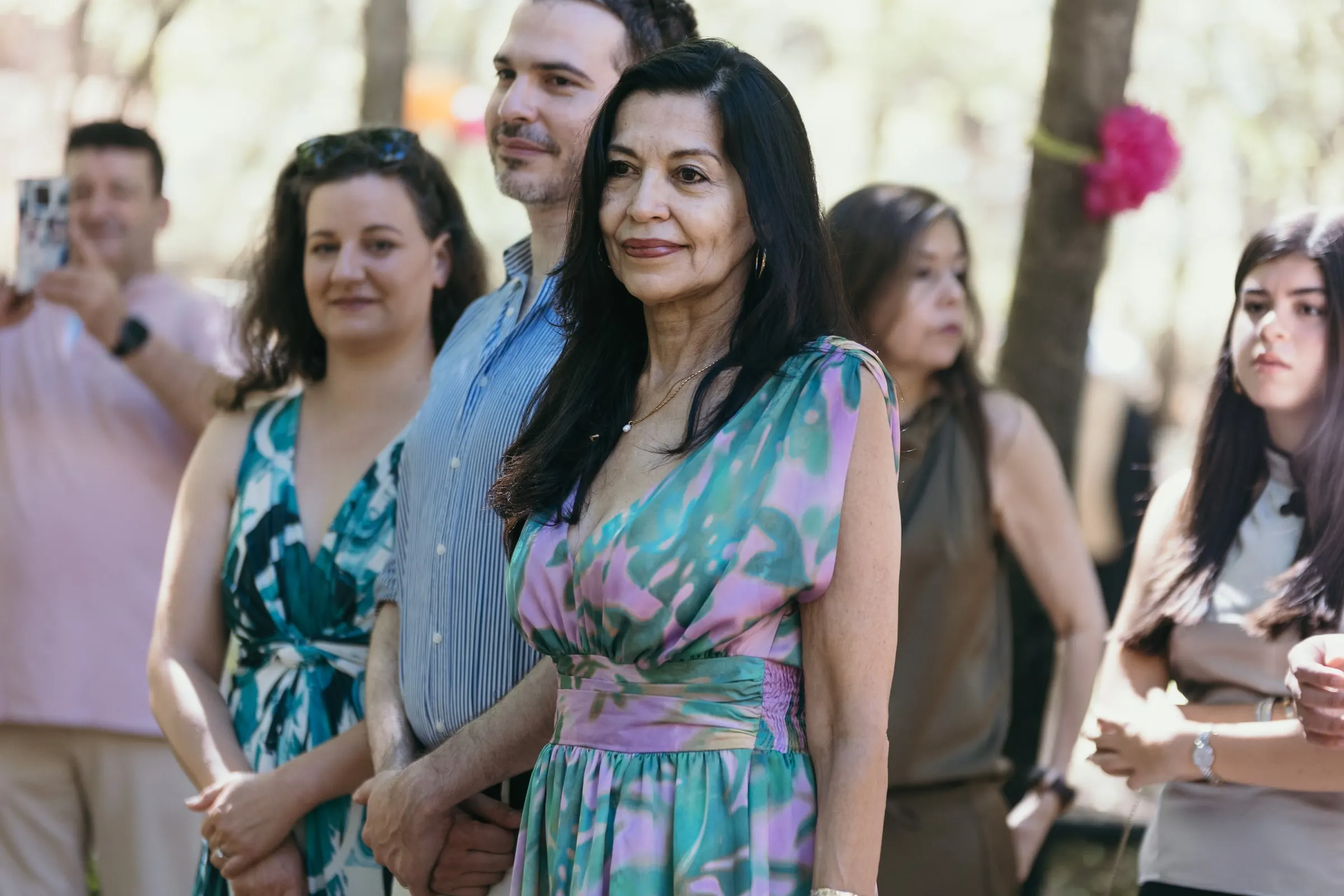 Los invitados de pie ven llegar a la pareja bajo los árboles
