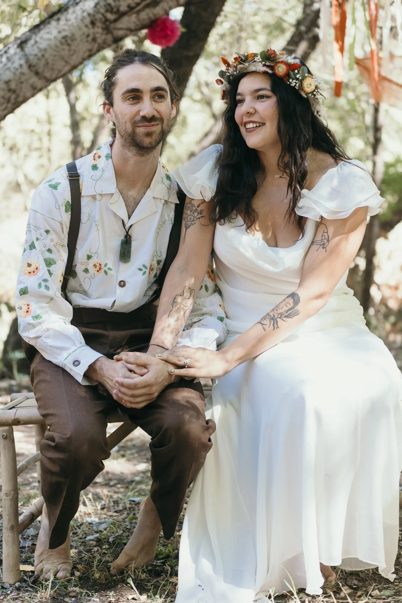 La pareja de la mano en taburetes de madera en su ceremonia en el bosque