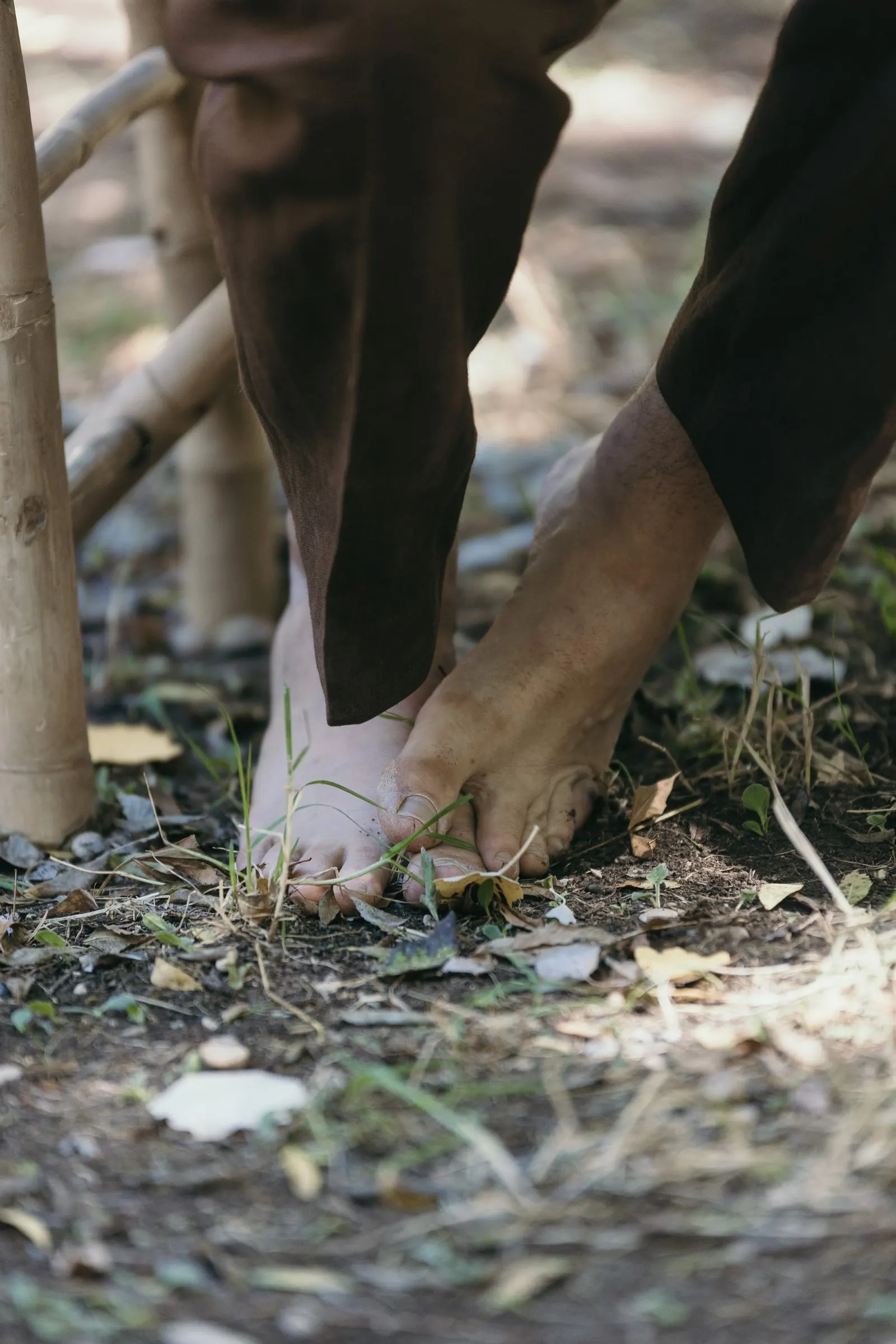 Los pies descalzos del novio junto a un banco de bambú en la ceremonia
