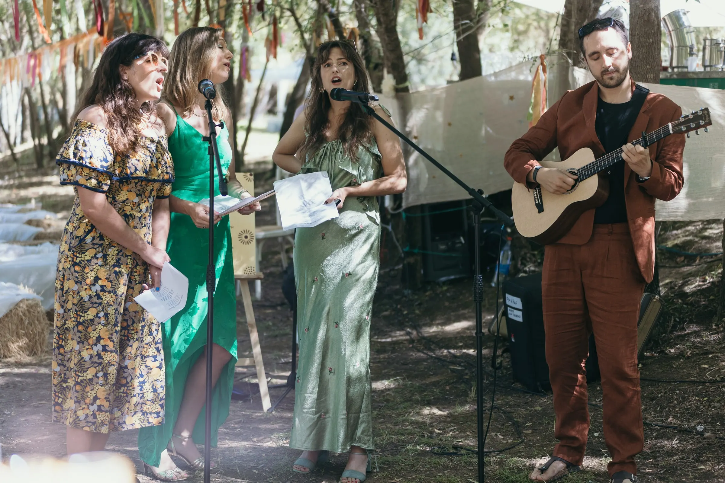 Amigas cantan a la pareja al micrófono con un guitarrista de traje teja