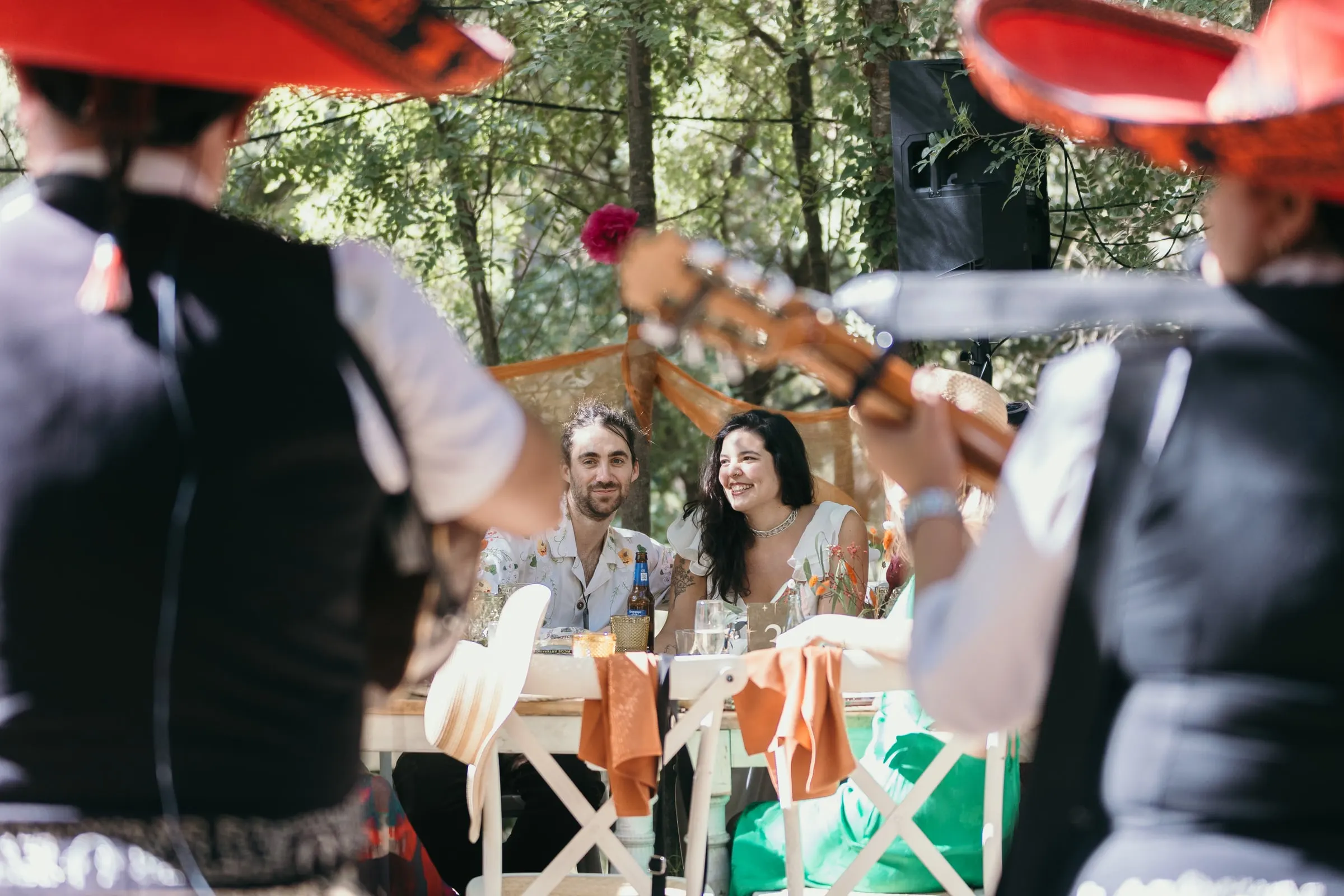 Músicos con sombreros rojos dan una serenata a la pareja en su mesa