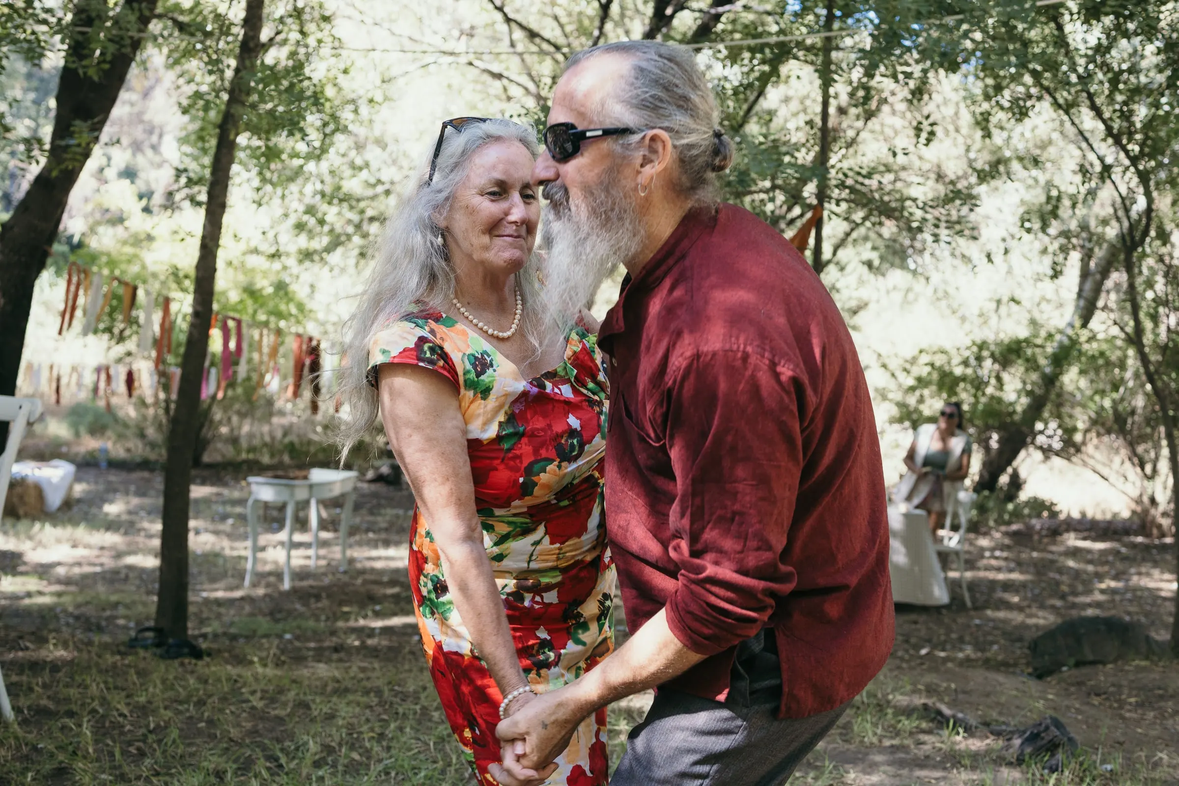 Una pareja mayor baila a la sombra de los árboles por la tarde