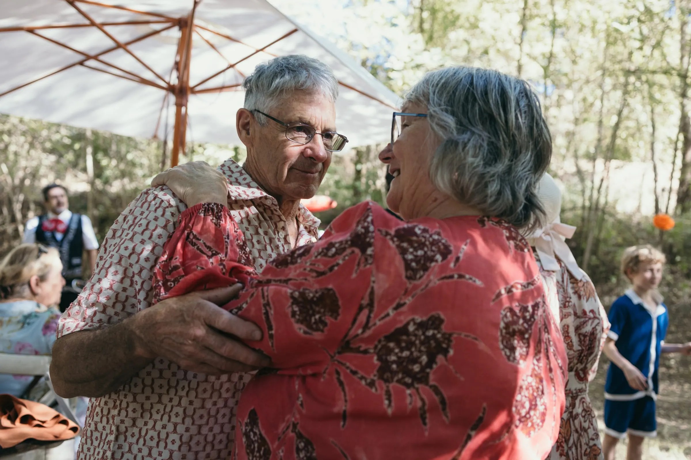 Los padres del novio se abrazan bajo una sombrilla en la fiesta