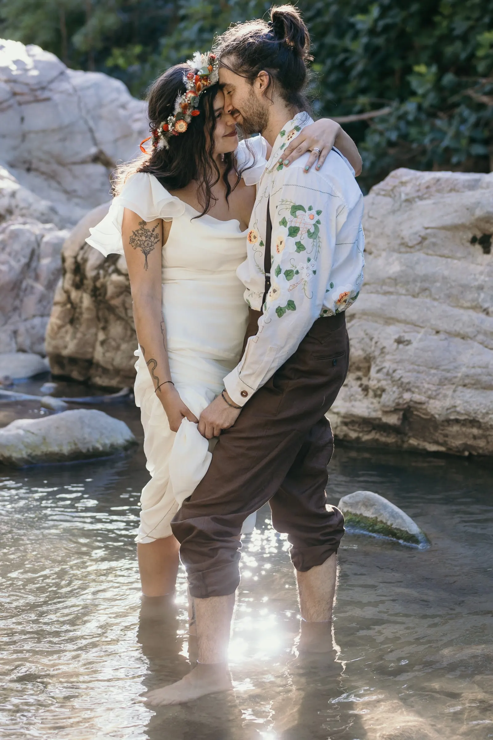 Couple standing in the clear water of the Guadiaro with trousers rolled up