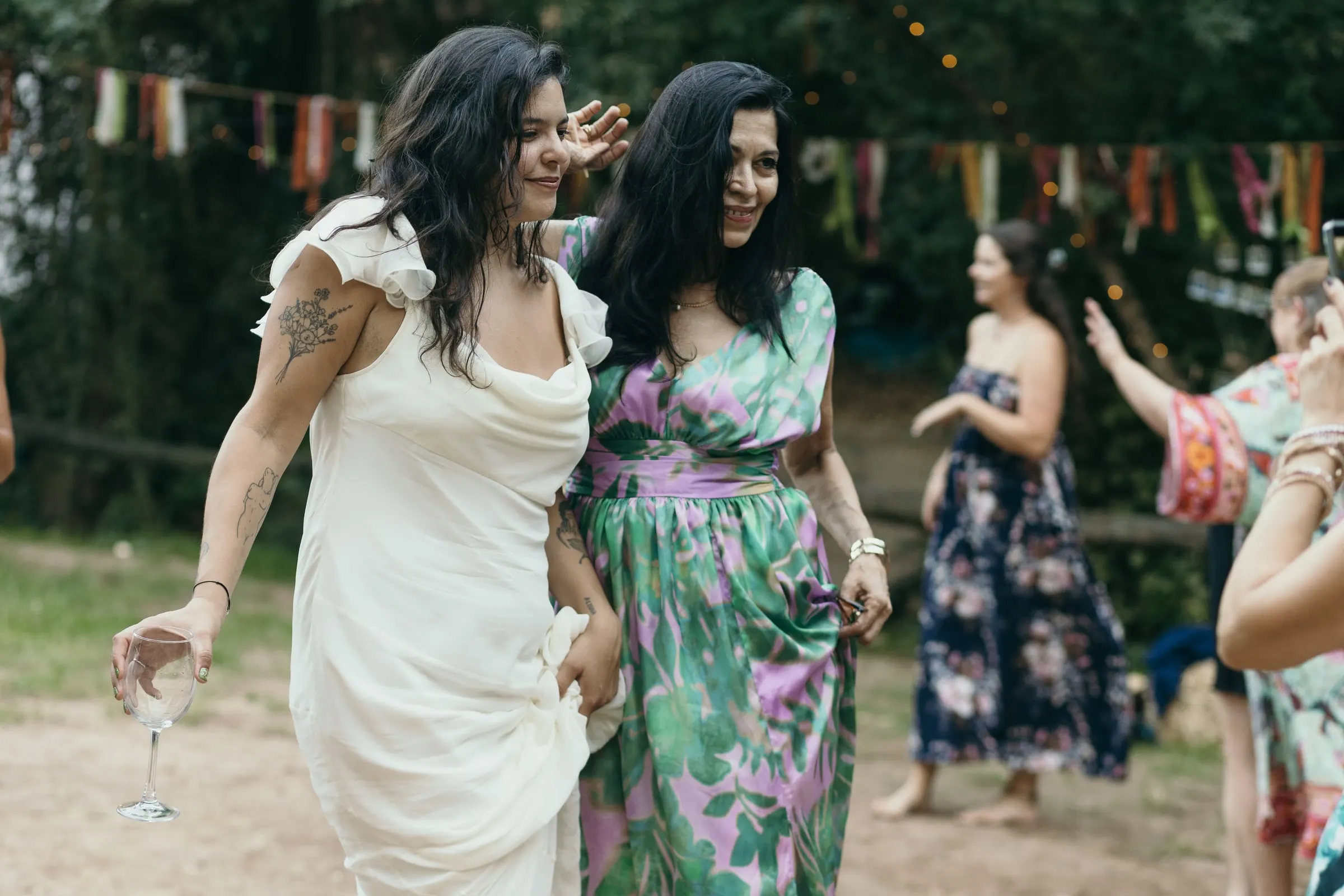 La novia baila con una invitada de mono de flores bajo los banderines