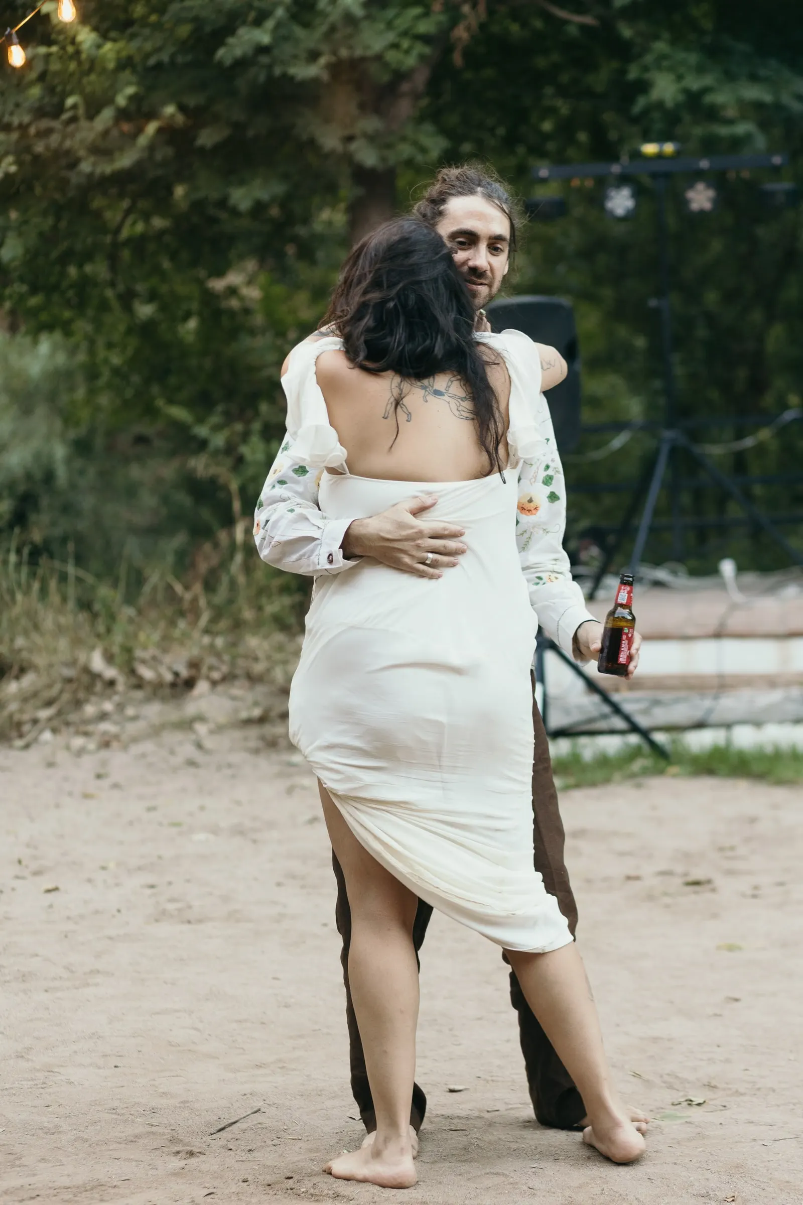 El novio abraza a la novia mientras bailan al caer la tarde