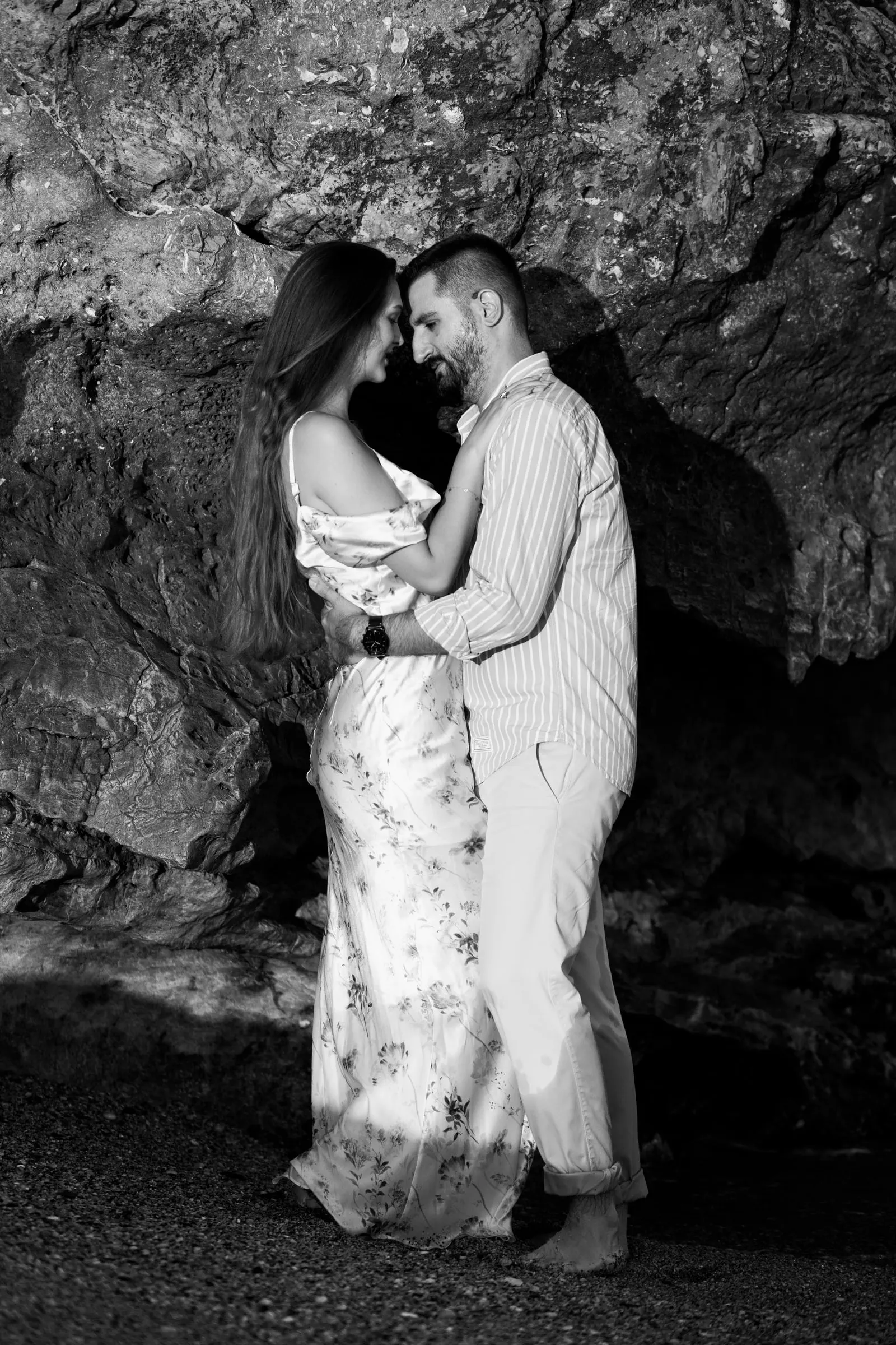 La pareja abrazada ante una roca oscura, en blanco y negro, en la playa de Nerja