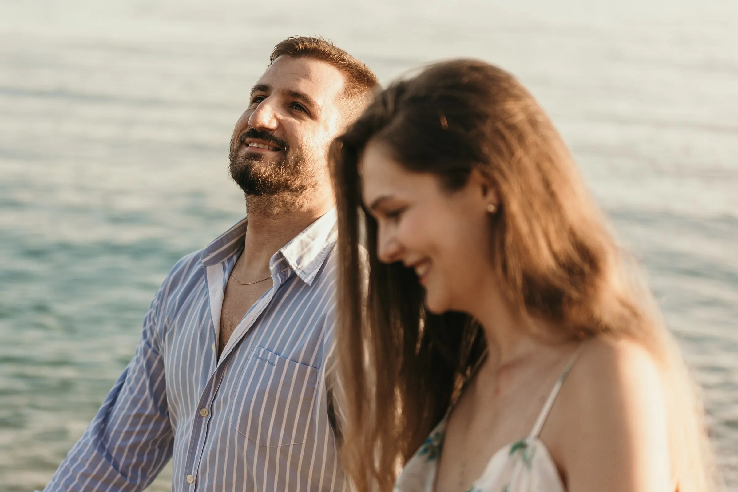 Él ríe con los ojos cerrados y ella sonríe a su lado frente al mar, en la playa de Nerja