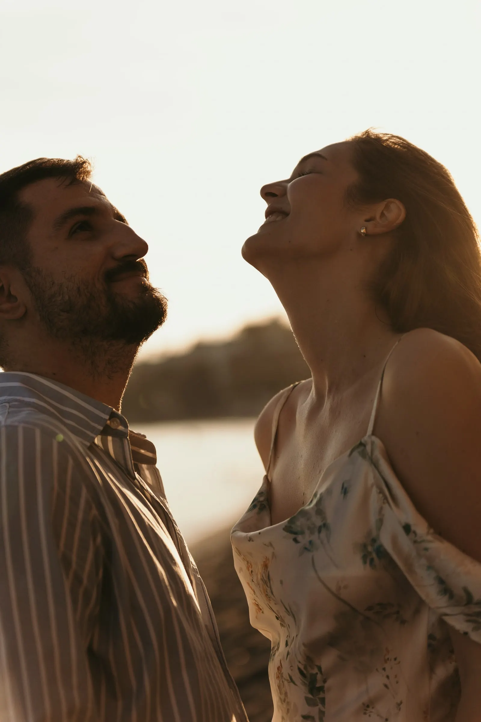 La pareja ríe con la cabeza echada hacia atrás bajo la luz dorada, en la playa de Nerja