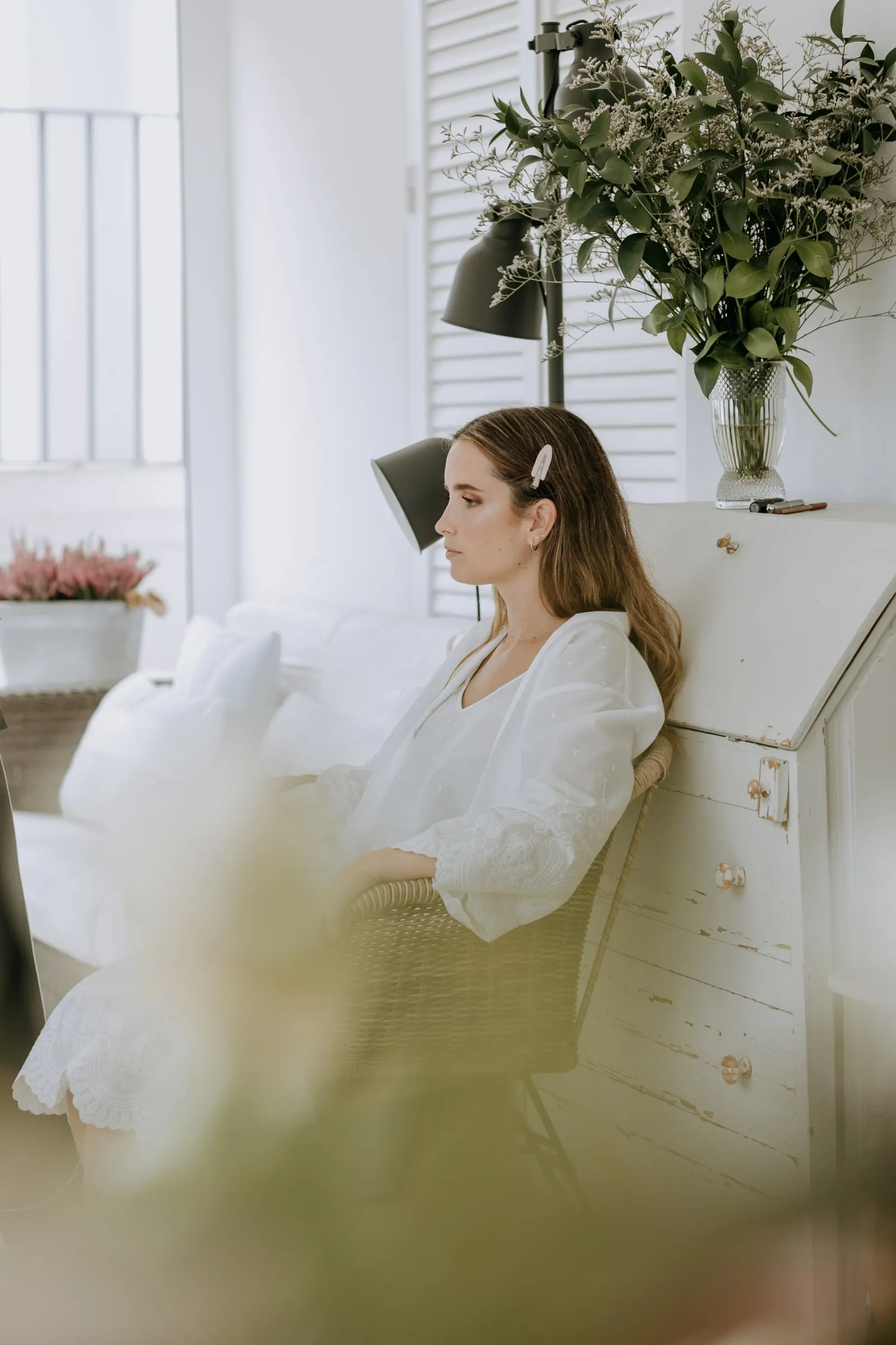 Bride in a white robe sitting by the window while she gets ready in Sotogrande