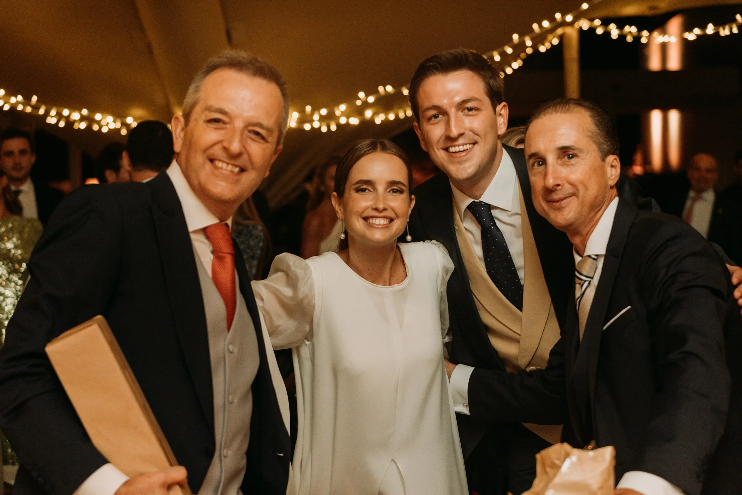 Bride posing with three men in morning suits under the tent at the party in Sotogrande