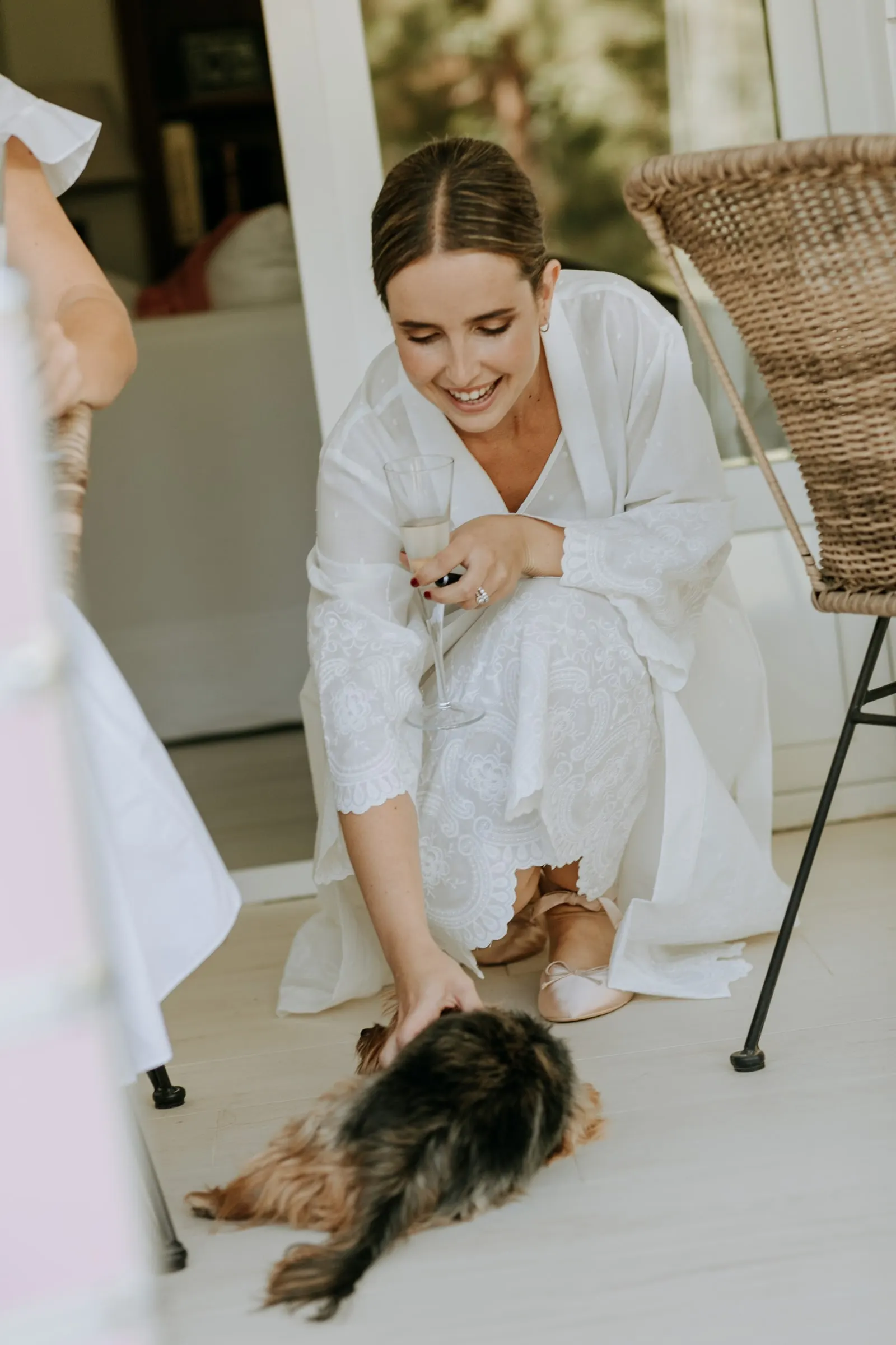 Bride in her robe crouching to stroke the family dog