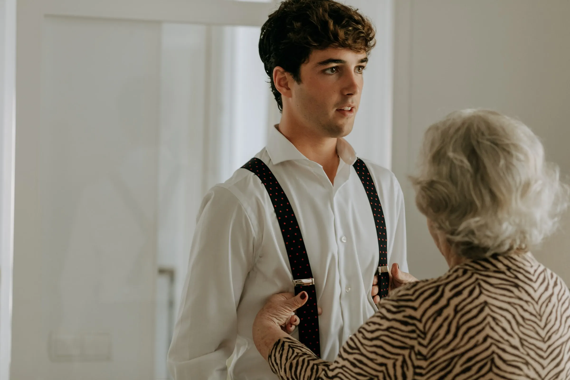Grandmother adjusting her grandson's braces before the wedding