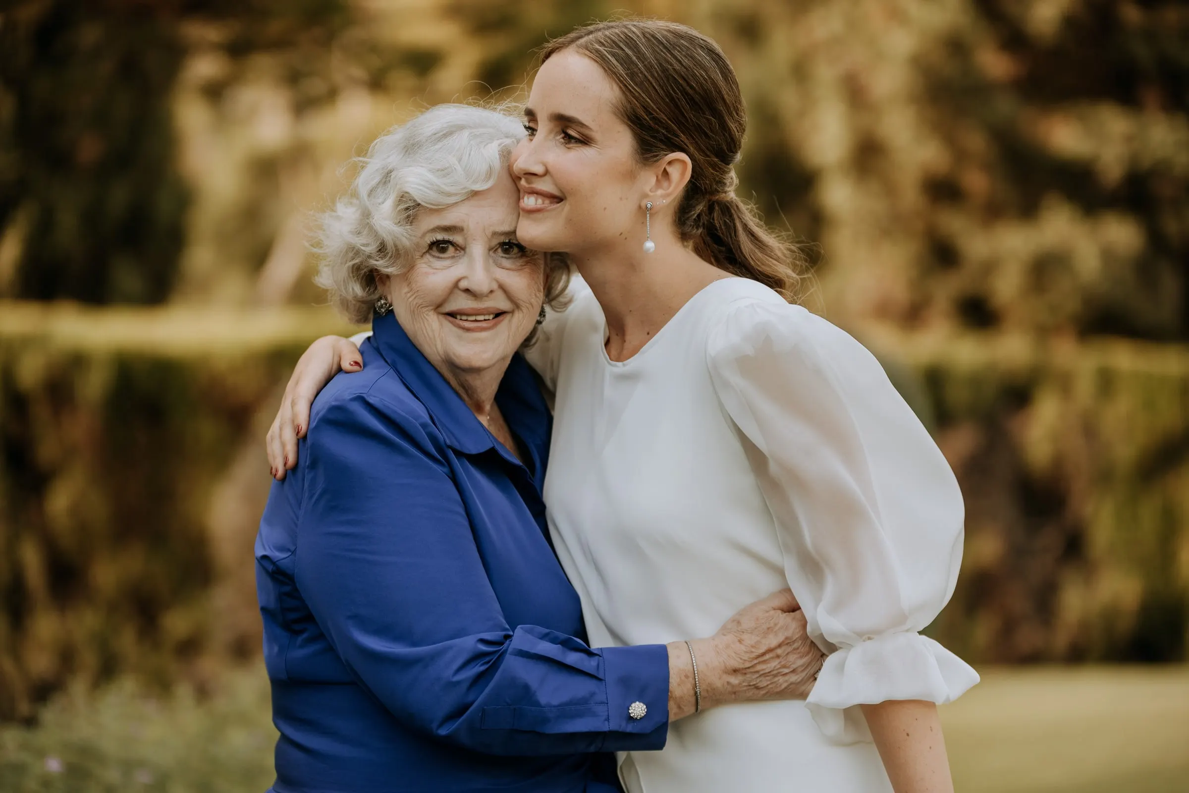 Bride hugging her grandmother in a blue blouse in the garden