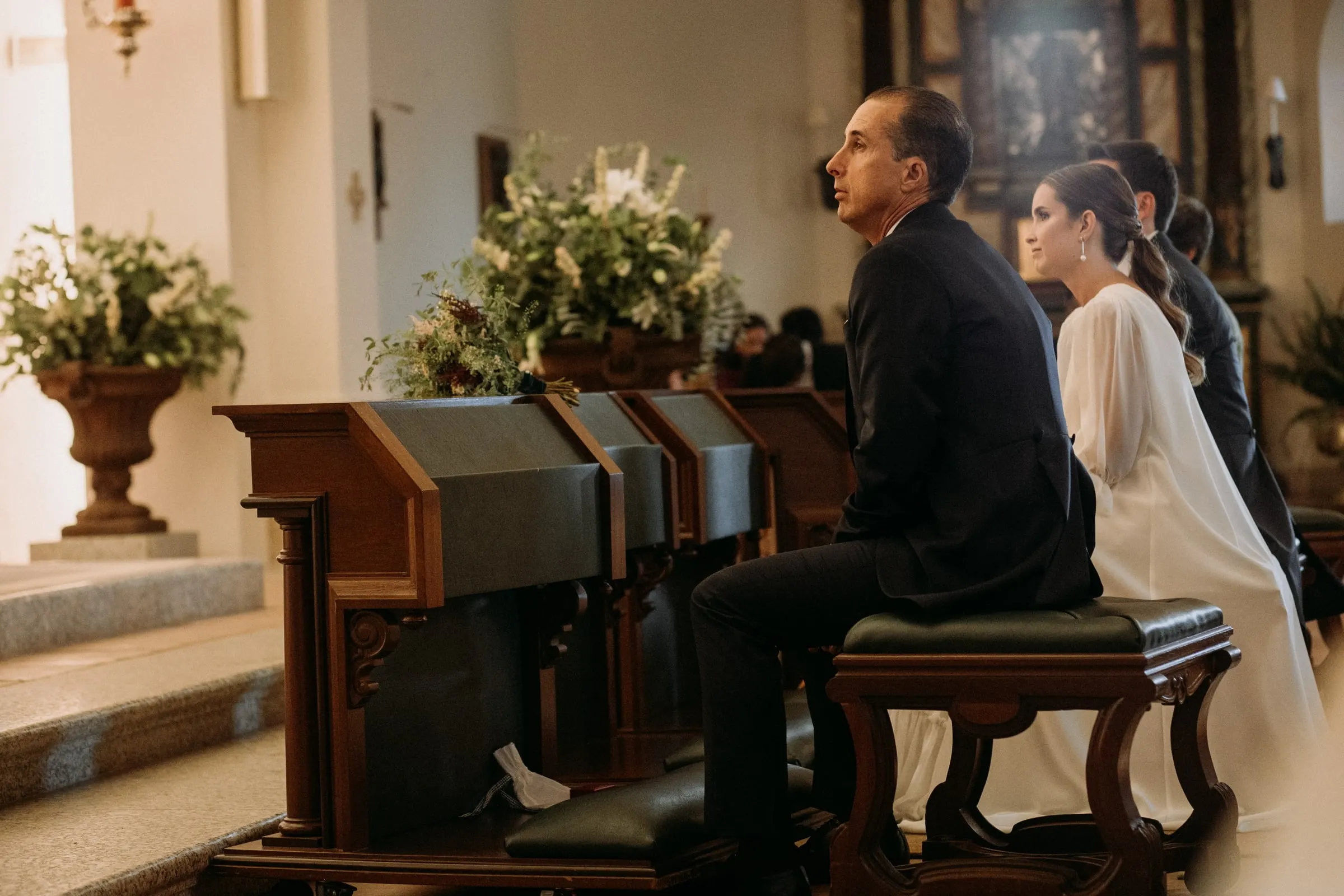Bride and groom seated at the kneeler in front of the altar