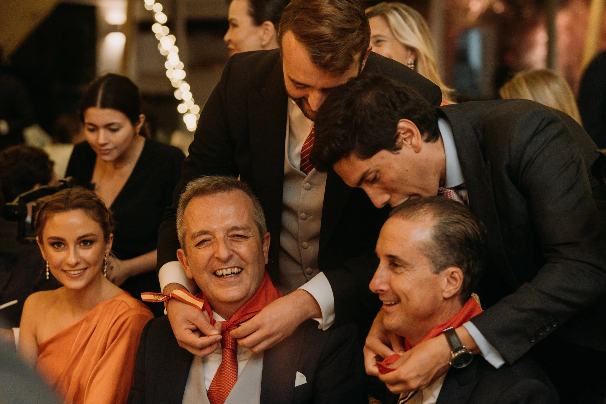 Friends tying red neckerchiefs on two guests at dinner