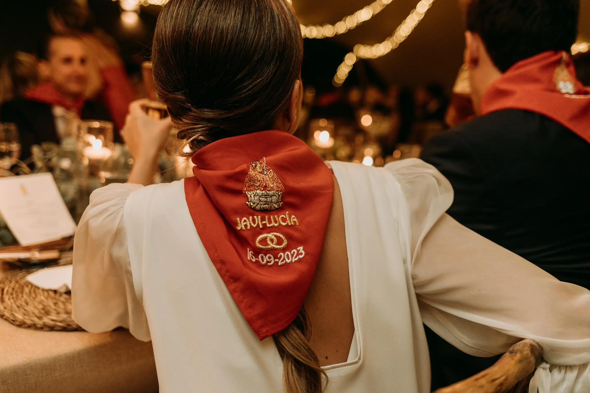 Red neckerchief embroidered 'Javi-Lucía 16-09-2023' on the bride's back