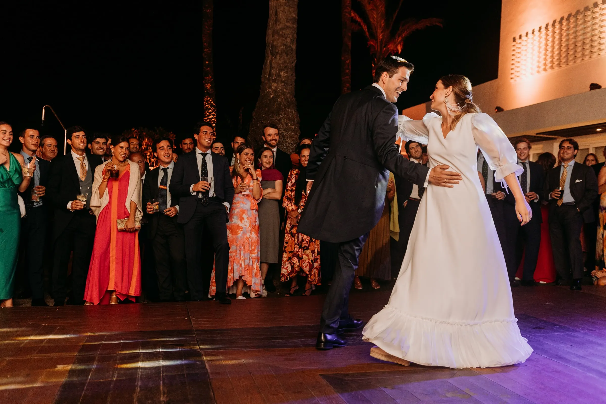 Bride and groom dancing on the wooden floor surrounded by guests in Sotogrande