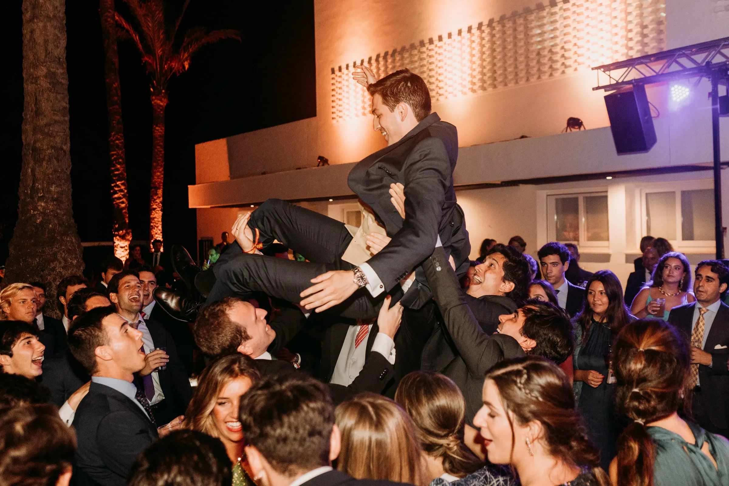 Groom lifted in the air by his friends on the dance floor