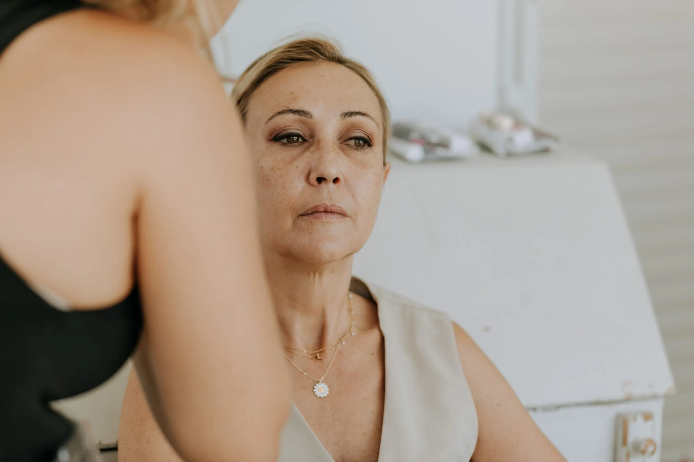 Blonde guest with her eyes half closed during her make-up in the white room