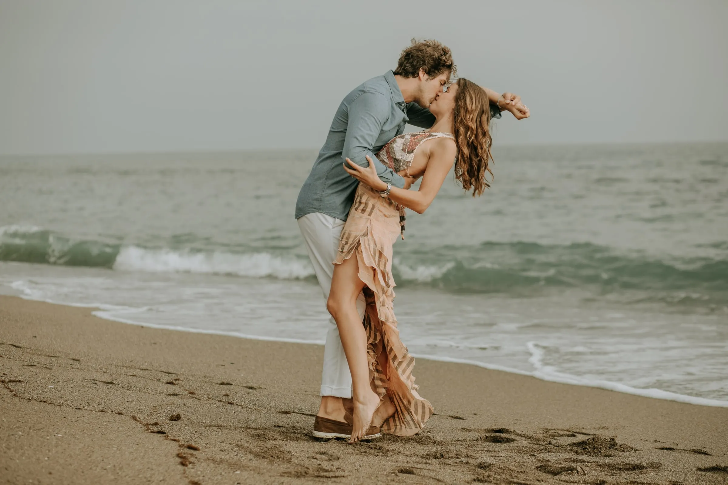 Arnaud inclina a Lauren para besarla en la orilla, sesión preboda en la playa de Sotogrande