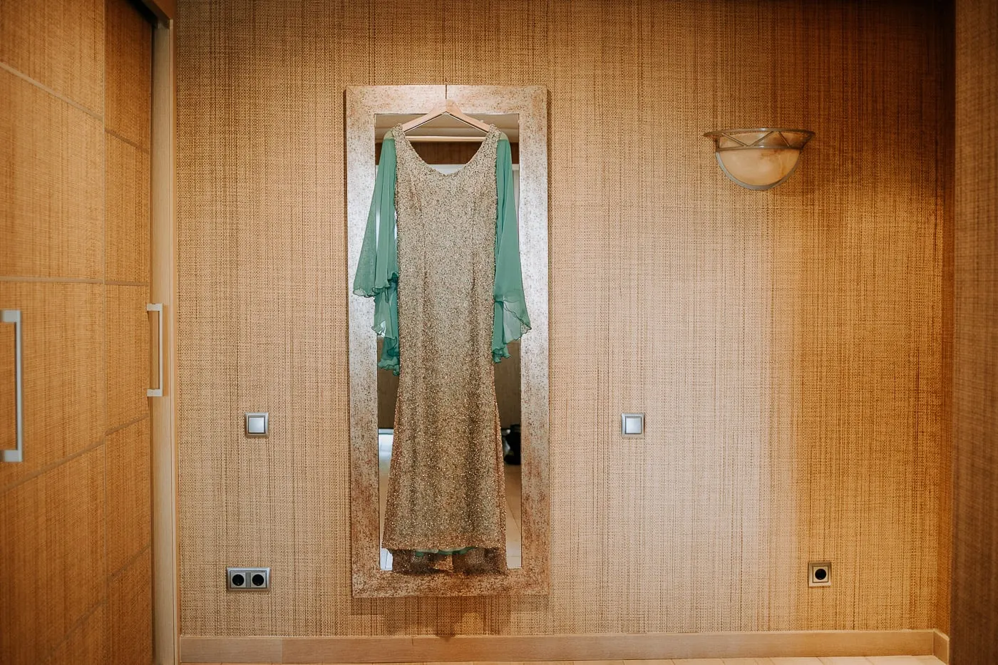Vestido plateado con capa turquesa colgado del espejo del armario