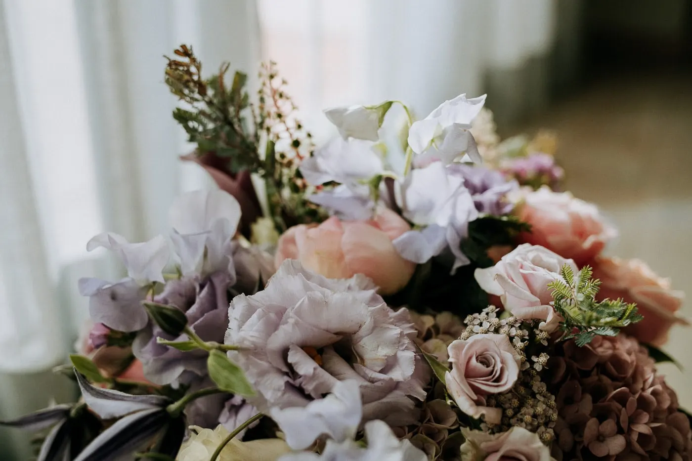 Ramo de novia de flores lilas, rosas y malvas sobre una mesa