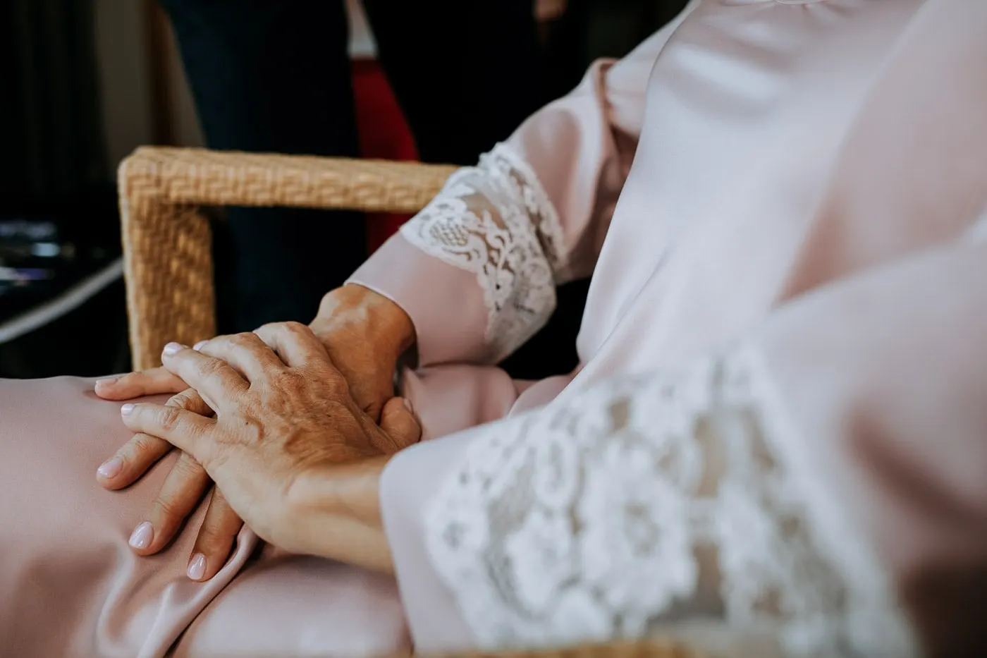 Las manos de la novia sobre el regazo, junto al puño de encaje de la bata