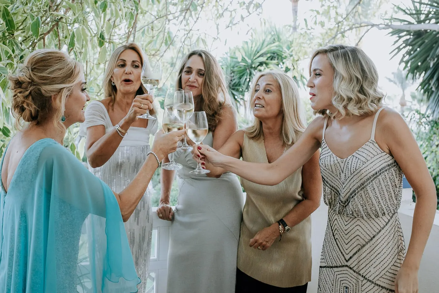 La novia y sus amigas brindan con vino blanco en el balcón