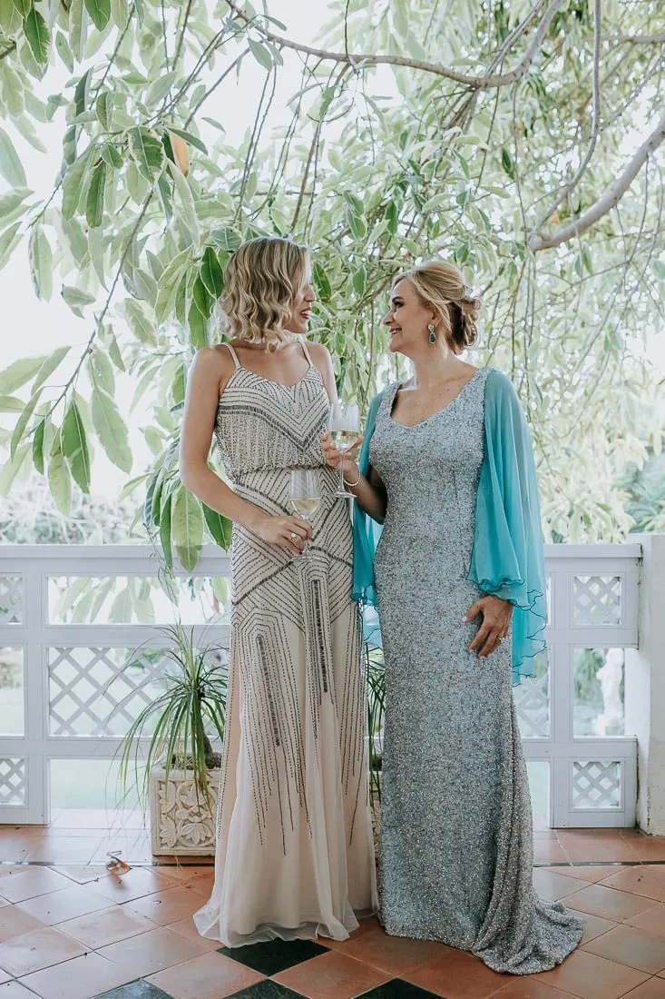 La novia con una amiga de vestido de abalorios en la terraza