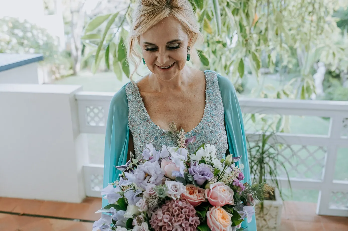 La novia mira su ramo de tonos lila y melocotón