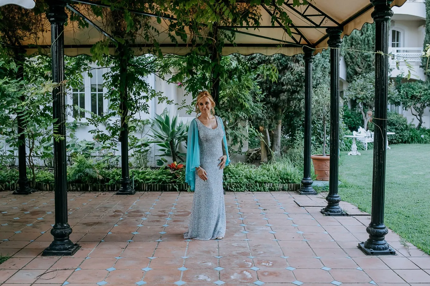 La novia bajo una pérgola de hierro en los jardines del hotel