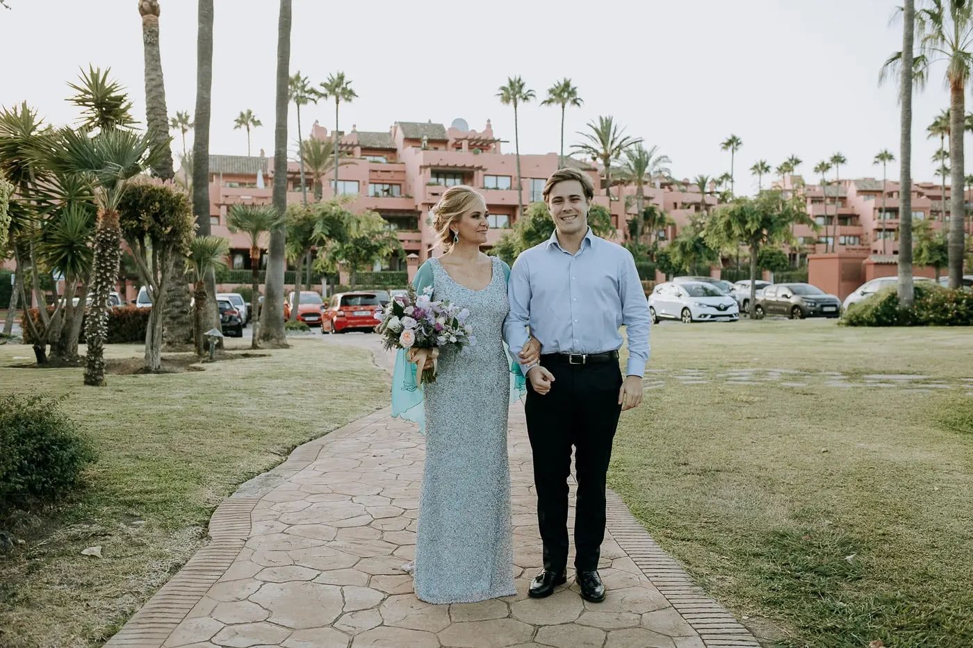 La novia llega del brazo de un joven con camisa azul