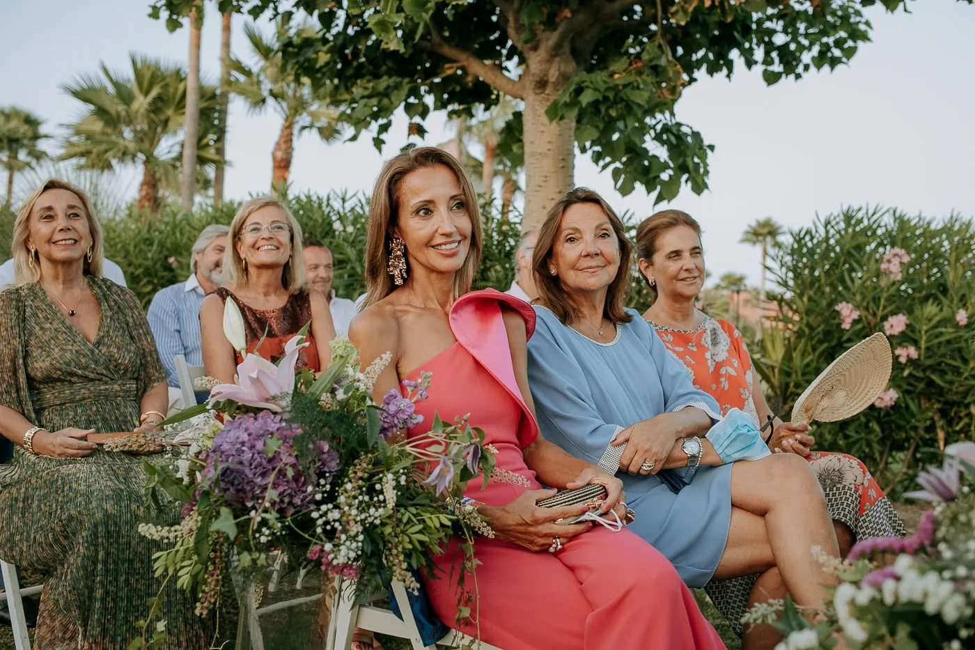 Invitadas entre las flores de las sillas durante la ceremonia