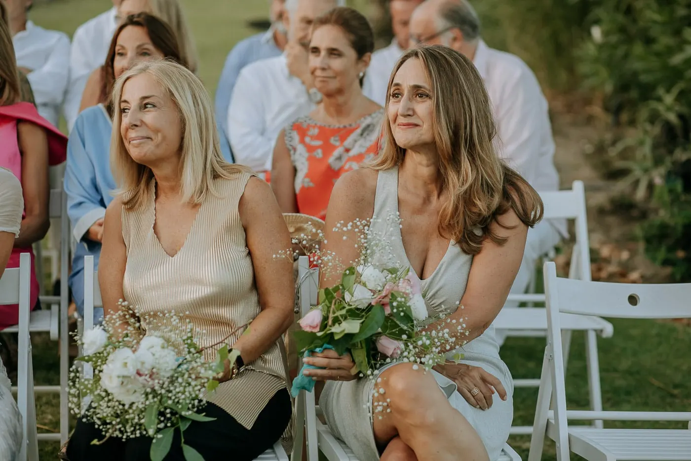 Dos amigas con ramos sonríen durante la ceremonia