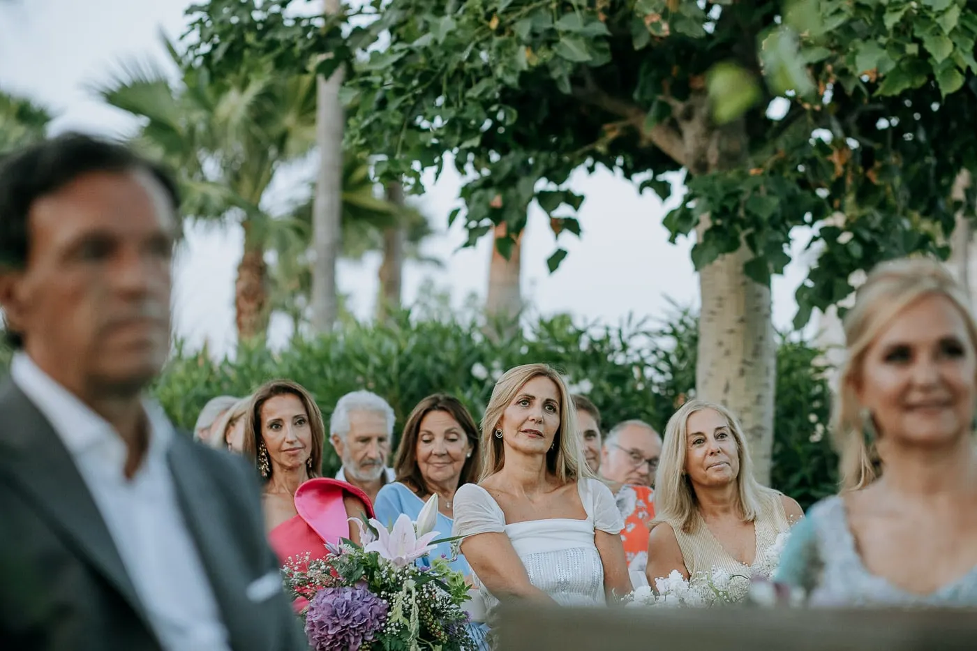 Invitadas mirando la ceremonia por detrás del hombro del novio