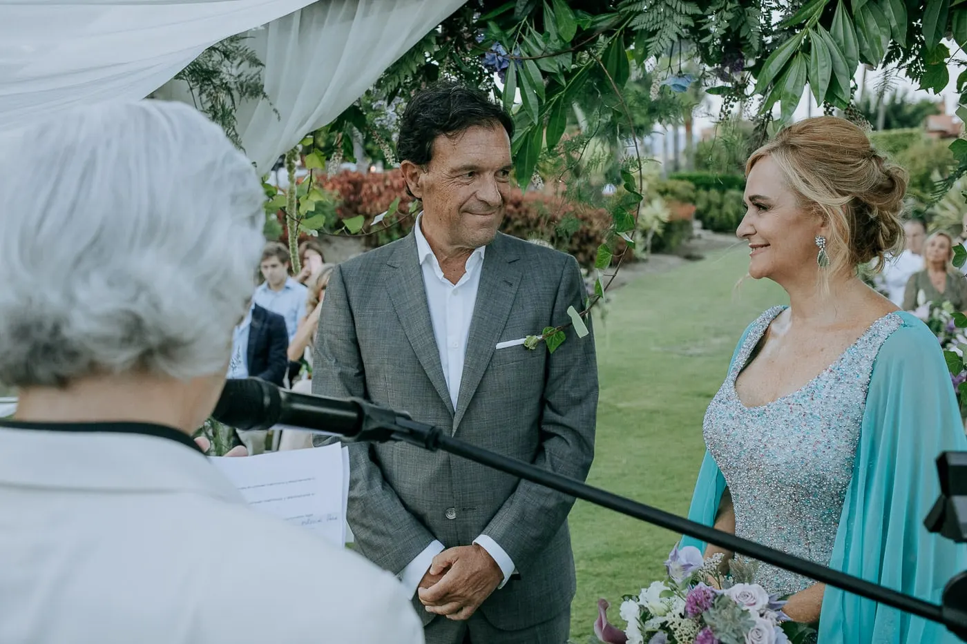 El novio y la novia sonríen al oficiante