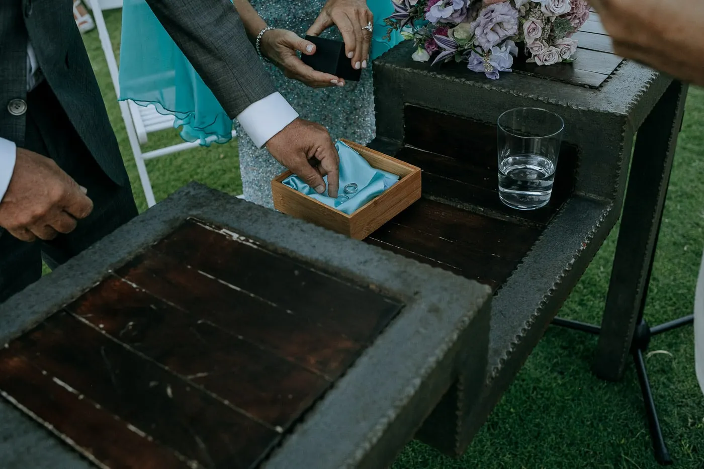 Unas manos sacan los anillos de una caja con un paño turquesa